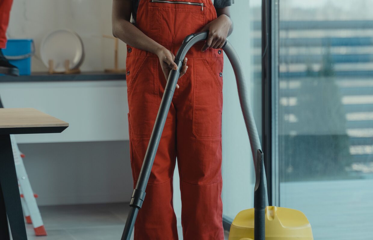 Schoonmaakmedewerker stofzuigt een werkruimte