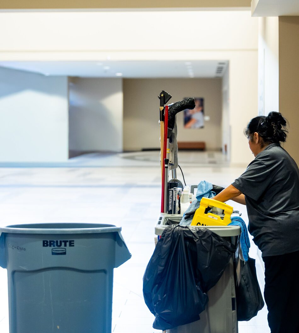 Schoonmaakkar met materialen in de gang van een kantoorpand